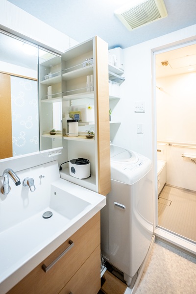 洗面の工事後。LIXILクレヴィを採用。洗濯機上にかごで収納している