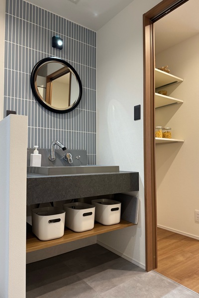 LIXILカスタムバニティとタイルで仕上げた洗面台、丸いミラーでかわいく